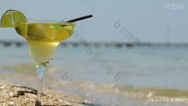 站在海边的沙滩上，手把酸橙片放在鸡尾酒杯上的特写镜头